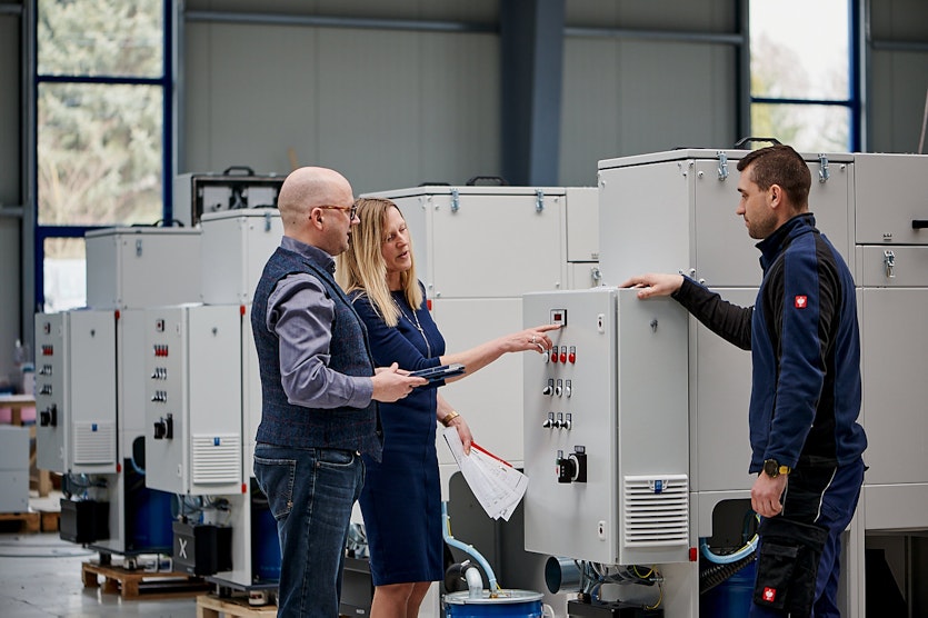 Three people at a fume extraction system, talking