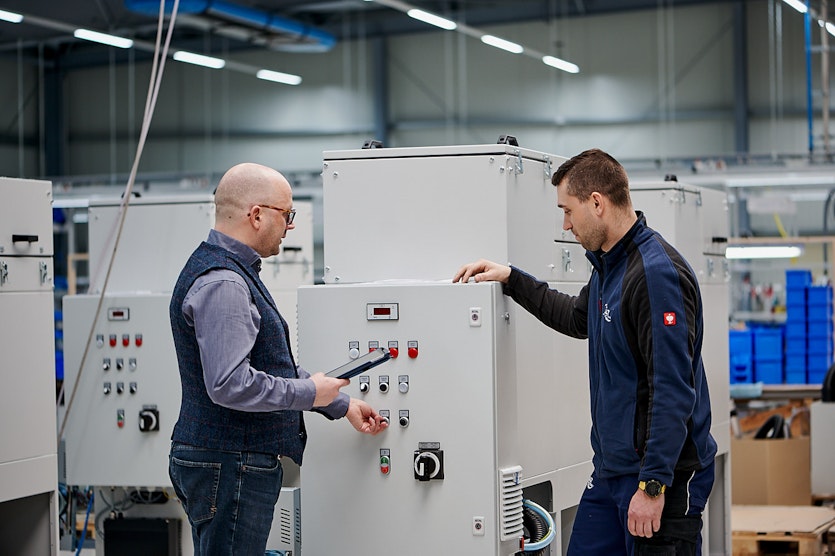 Two men check a system, talking to each other