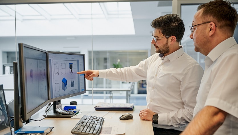 Two men are checking information on a screen
