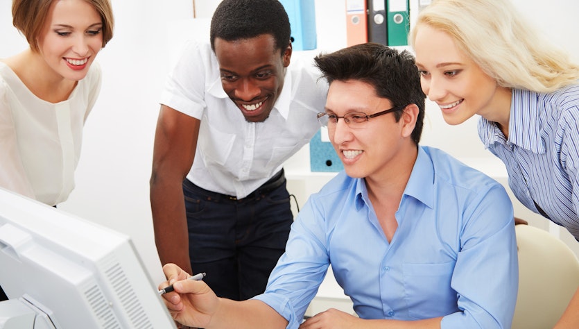 Four people sitting in front of a PC discussing