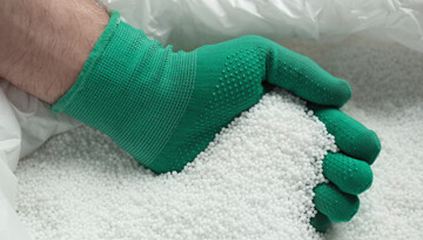 Hand with a glove in a sack of fertilizer